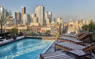 Una piscina al aire libre, sombrillas, sillones reclinables de piscina