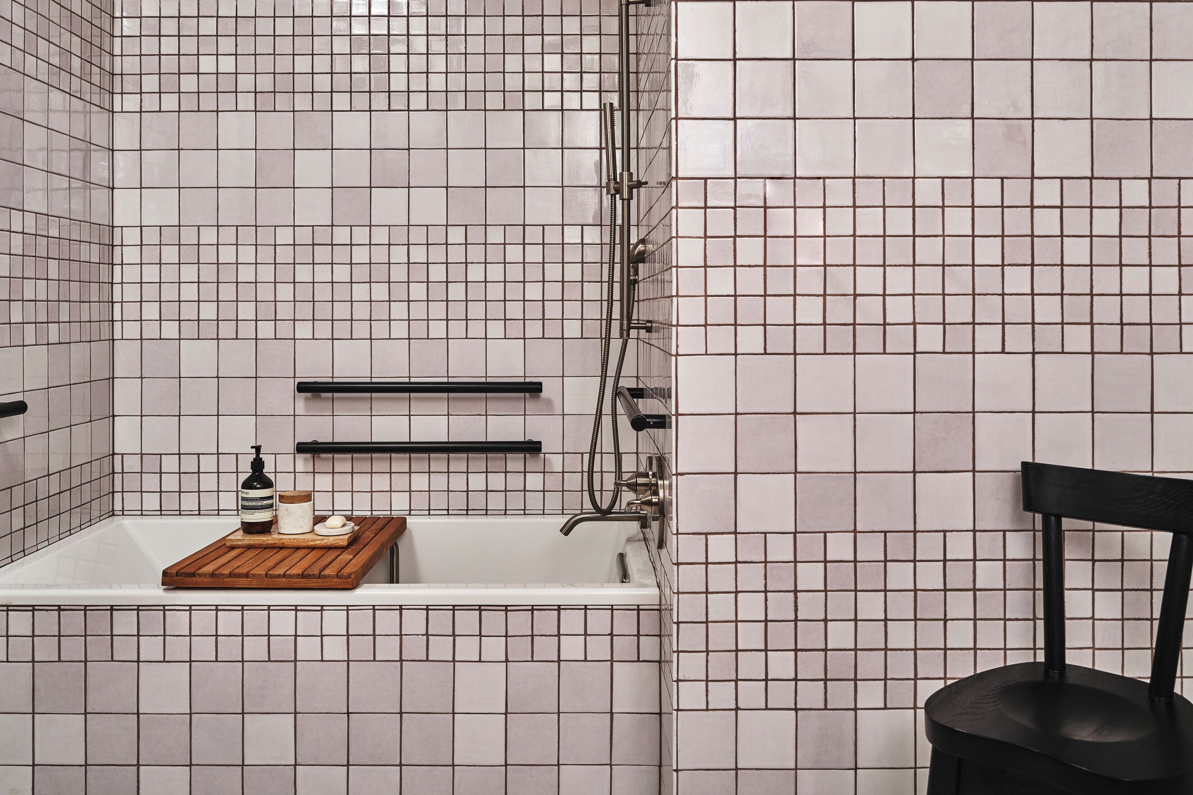 A bathroom with a bathtub, a shower, and a chair.