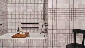 A bathroom with a bathtub, a shower, and a chair.
