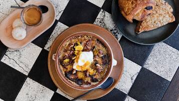 A checkered table with a bowl of soup, a croissant, and a cup of coffee.