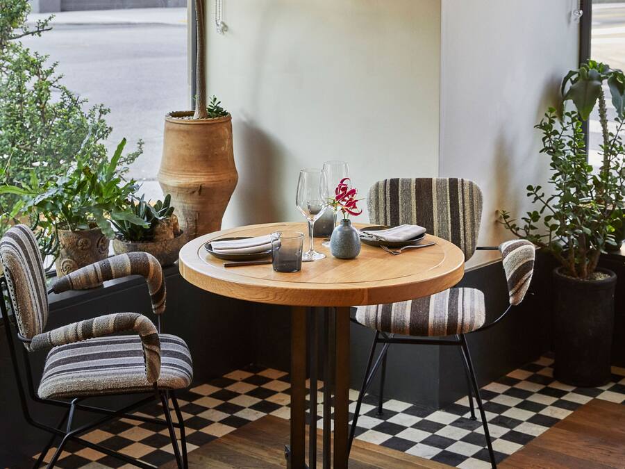 Un comedor acogedor con una mesa redonda de madera, sillas tapizadas a rayas y plantas en macetas.