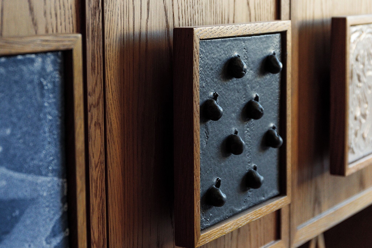 A wooden cabinet with a textured surface and a section with black knobs.