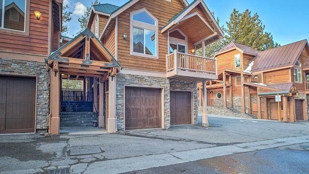 A multi-story wooden house with a stone foundation, large garage doors, and a balcony. - Mammoth Lakes Townhome - 10-Min Walk to Village! (Mammoth Lakes)