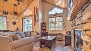 A spacious living room with a large sofa, a wooden coffee table, and a stone fireplace. - Mammoth Lakes Townhome - 10-Min Walk to Village! (Mammoth Lakes)