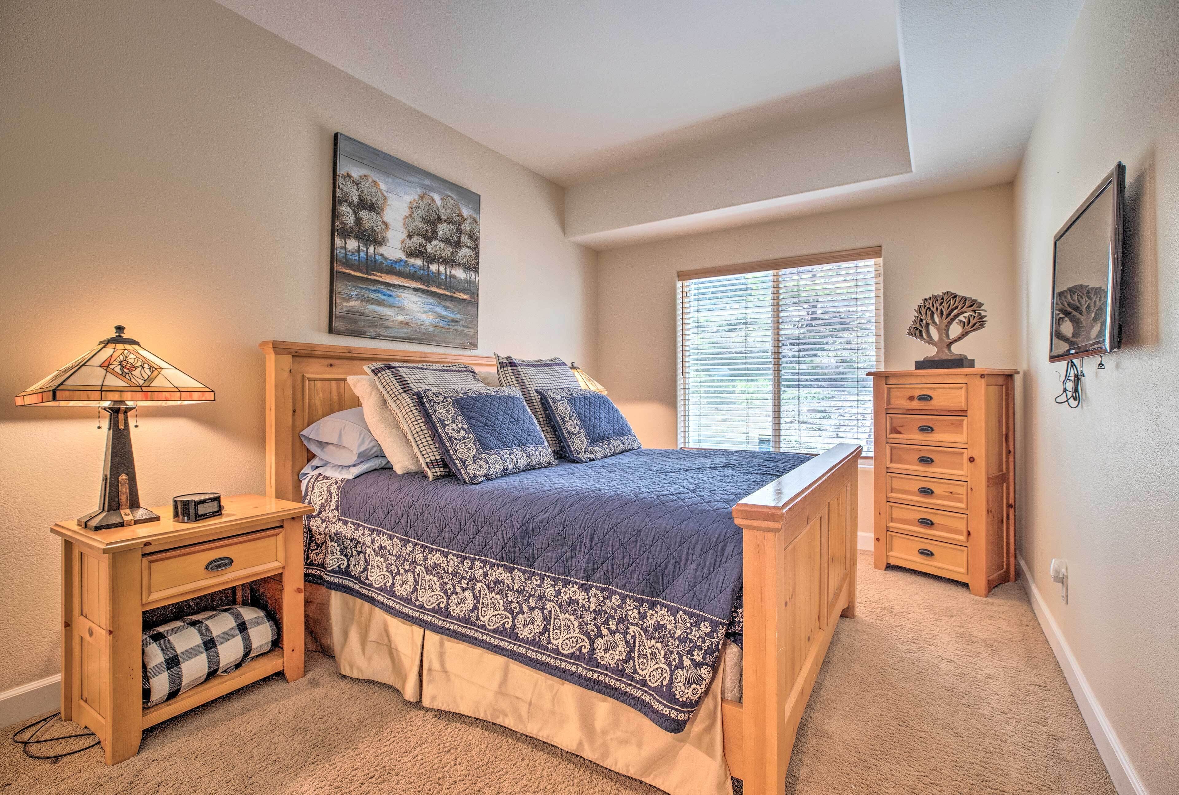 A bedroom with a bed, nightstand, dresser, and a window with blinds.