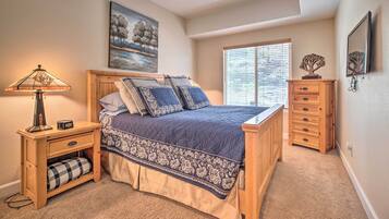 A bedroom with a bed, nightstand, dresser, and a window with blinds.