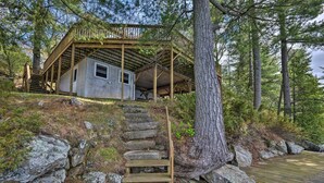 A cabin with a wooden deck and a staircase leading to a covered porch.
