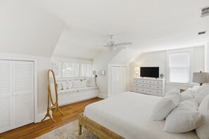 A bedroom with a bed, a dresser, a television, a window with blinds, and a ceiling fan. - Historic Cottage Greene Square – Walk to River Street.Jazz Festival Availability (Savannah)