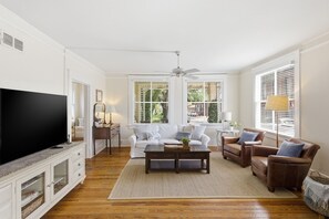 Un salon avec un téléviseur, un canapé, une table basse et des fauteuils.