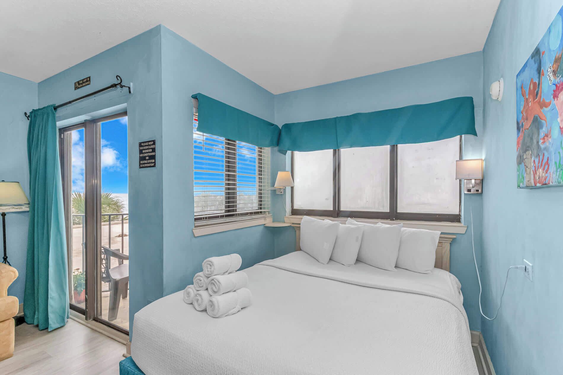 Une chambre à coucher avec un lit, une fenêtre avec des stores, une porte avec une pancarte et une vue sur l’extérieur.