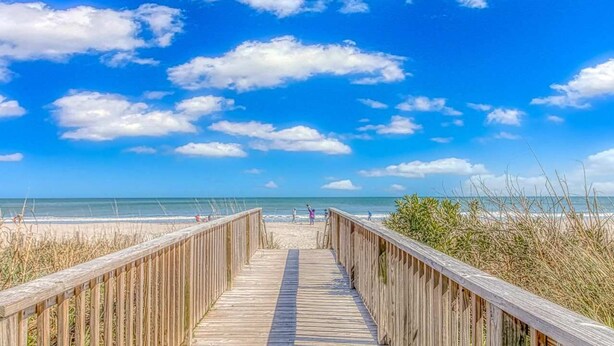 A wooden boardwalk leading to a beach with clear skies and ocean views. - Palace 105 (Myrtle Beach)