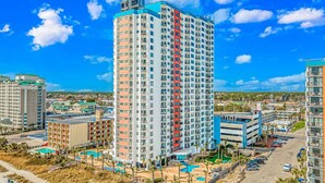 A high-rise hotel with multiple floors, a swimming pool area, and a parking lot. - Palace 105 (Myrtle Beach)