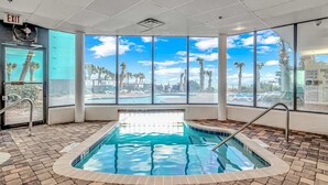 A pool area with a clear view of palm trees and a blue sky through large windows. - Palace 105 (Myrtle Beach)