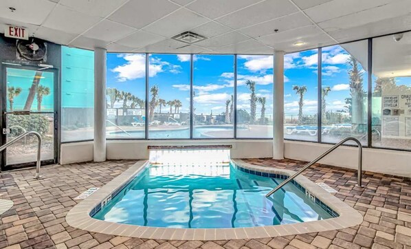A pool area with a clear view of palm trees and a blue sky through large windows.