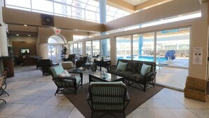 A spacious lobby with comfortable seating, large windows, and a view of the pool area.