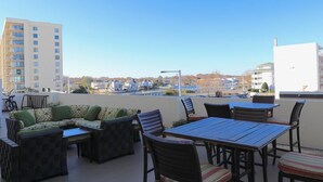 A rooftop terrace with outdoor furniture, including a sofa, chairs, and a table.