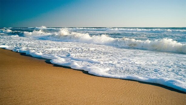A beach with waves crashing onto the shore.