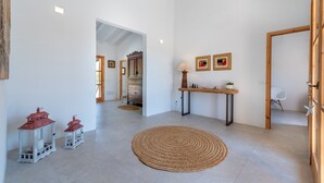 Una habitación amplia con un gran tapiz tejido, una mesa de madera con una lámpara y dos faroles rojos.