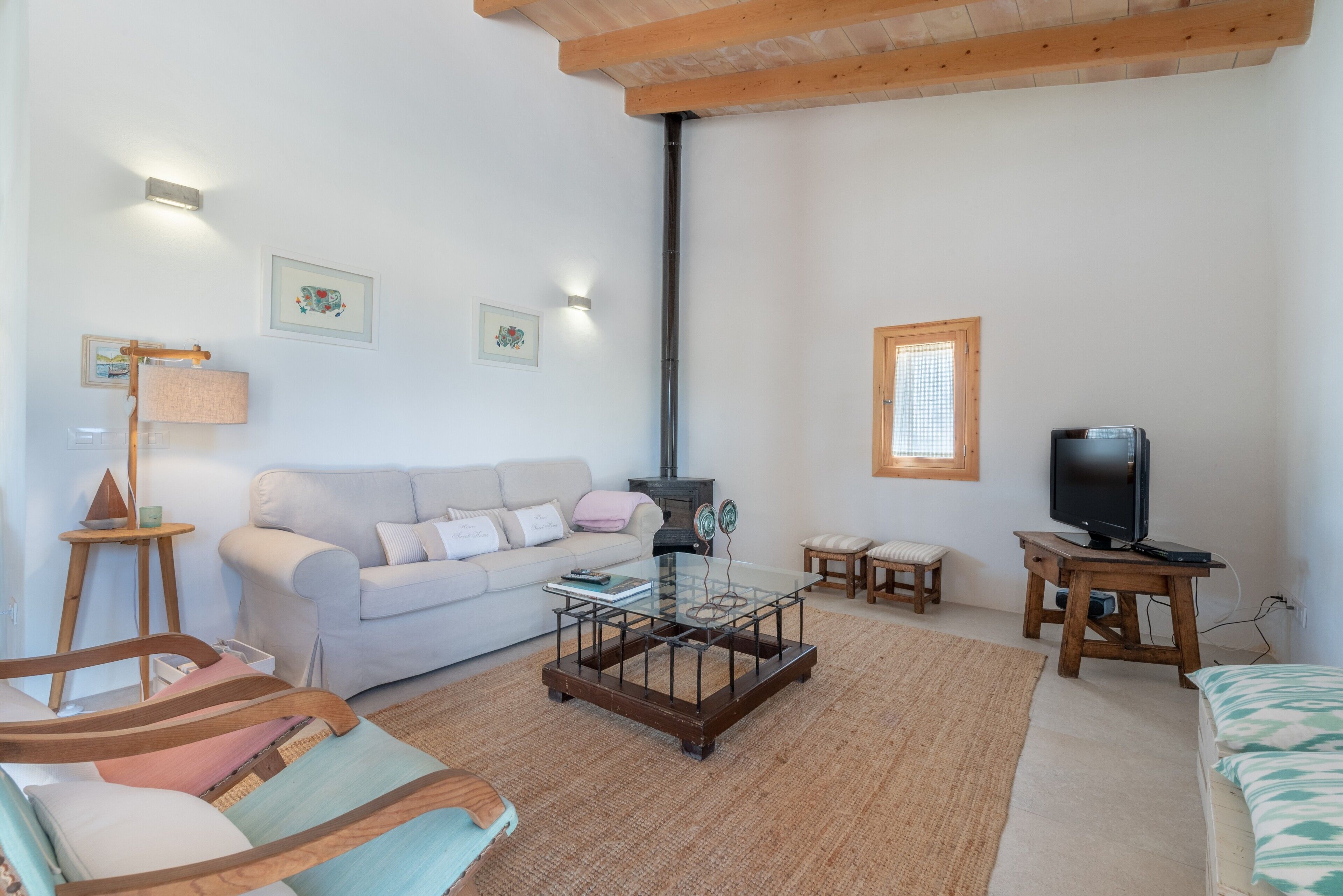 Ein gemütliches Wohnzimmer mit Sofa, Glastisch, Fernseher auf Holzfuß und Kamin.