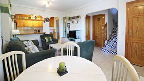 A compact living space with a dining table, chairs, a sofa, a television, and a staircase. - VM 6 - Duplex with private garden near the beach (Vera playa)