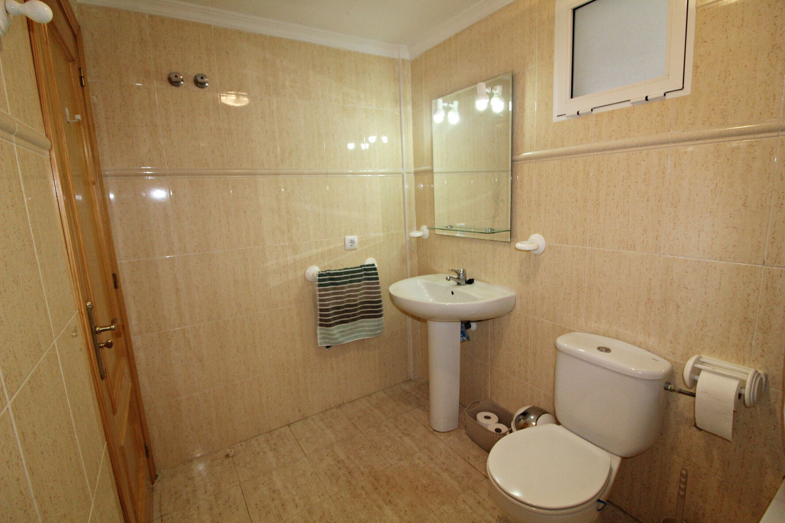 Ein Badezimmer mit Toilette, Waschbecken, Spiegel und Dusche.