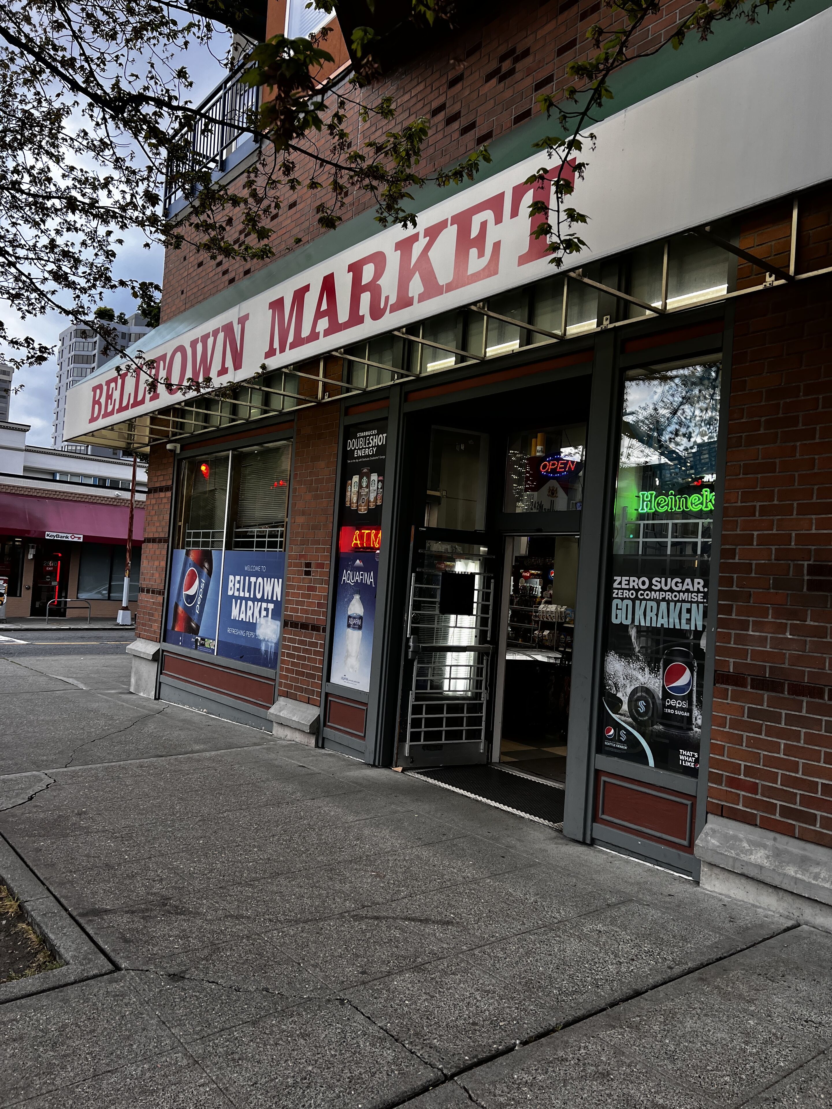 The exterior of the Belltown Market building with a large sign, storefront windows, and advertisements for Pepsi and Aquafina water.