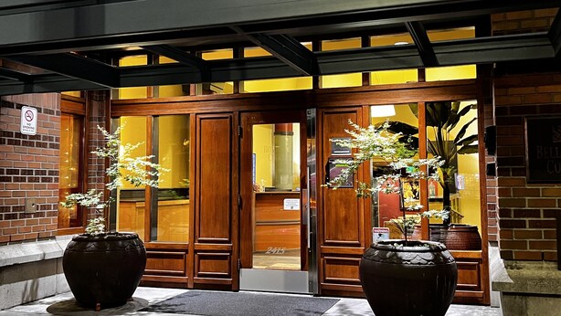 A hotel entrance with wooden doors and a brick facade. There are potted plants in front of the entrance. - Cozy home nearby most attractions Seattle center (Seattle)