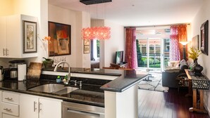 A modern kitchen with a central island, a dining area with a sofa and table, and a view of a garden through large windows. - Cozy home nearby most attractions Seattle center (Seattle)