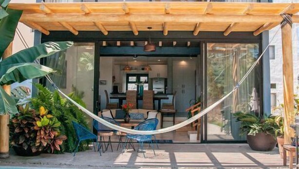 Uma casa moderna de dois andares com fachada de vidro, piscina e uma rede.