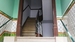 A staircase with a wooden handrail, a white wall with a decorative molding at the top, and patterned tiles on the walls. - Timor Guest House (Lisbon)