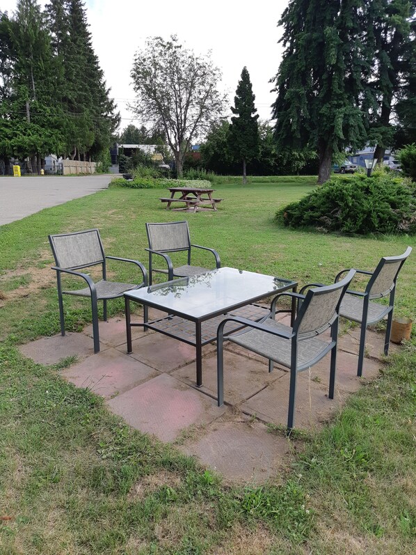 Mesa de piquenique com quatro cadeiras em uma área gramada.