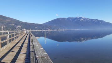 A wooden pier extending into calm water with a mountain in the background.
