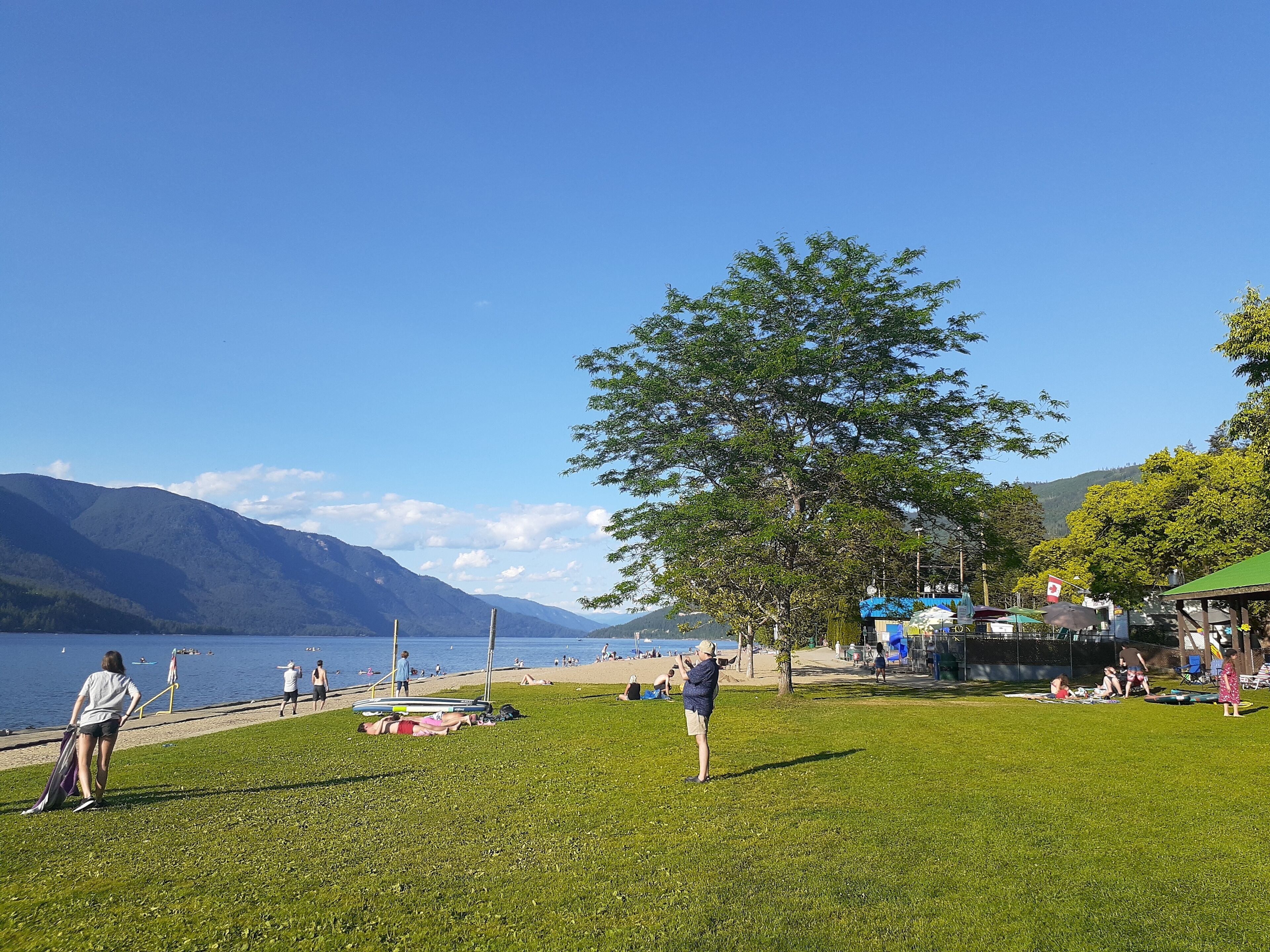 A grassy area with a lake and mountains in the background.
