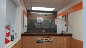 Un área de recepción con mostrador de madera, un reloj y un cartel que dice 'Welcome'.