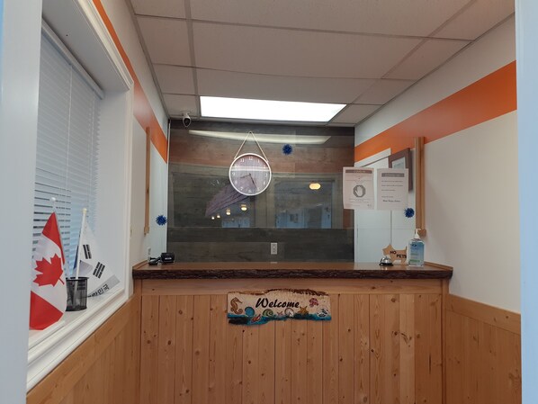 Un área de recepción con mostrador de madera, un reloj y un cartel que dice 'Welcome'.