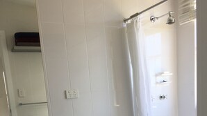 Casa de banho com sanita, lavatório e chuveiro.