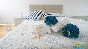A neatly made bed with a floral-patterned bedspread, two pillows, a starfish, and a bouquet of blue flowers. - Pavon House Blue -Villetta 80 meters from the sea, 3 km from Torre San Giovanni beaches (Alliste)