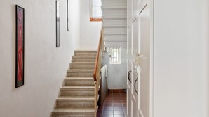 A staircase leading to a room with a window, a door with a handle, and a framed picture on the wall. - GuestHost - Pretty and cozy private house is located in the central area in Abano Terme, a few steps from the Cathedral of San Lorenzo, Piazza Mercato and the Urban Thermal Park, in a quiet and relaxing neighbourhood, spacious and perfect for 6 people. T (Abano Terme)