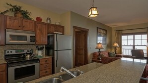 A kitchen with granite countertops, stainless steel appliances, wooden cabinets, and a hanging light fixture. - 2 Br: Soaring Eagle 211 (Snowshoe)