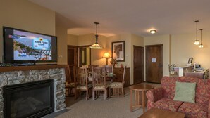 A living room with a fireplace, a television, a dining area with chairs and a table, and a sofa with a floral pattern. - 2 Br: Soaring Eagle 211 (Snowshoe)