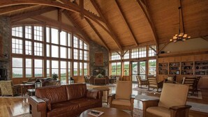 Une pièce spacieuse dotée de grandes fenêtres, d’une cheminée et d’un coin salon confortable avec un canapé et des fauteuils en cuir.