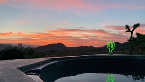 A swimming pool with a cactus sculpture and a mountain backdrop during sunset. - Joshua Tree Monument Entrance Outside Your Front Door (Joshua Tree)