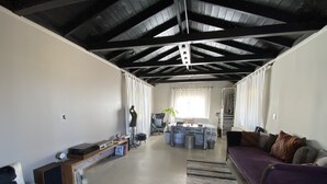 A spacious living area with a high ceiling, a sofa, a coffee table, and a dining table. - Joshua Tree Monument Entrance Outside Your Front Door (Joshua Tree)
