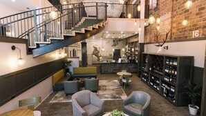 Un interior modern amb una escala, zones d'estar i una barra amb prestatges per a vi.