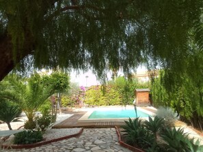 A pool area with a stone pathway, surrounded by various plants and trees. - Casa Maria with Mediterranean garden (San Juan de Alicante)