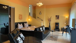 Ein modernes Wohnzimmer mit Sofa, Bett, Kamin und Essbereich.