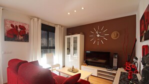 A living room with a red sofa, a television, a cabinet, and a wall clock. - Al 317 - Penthouse near the beach with terrace (Vera playa)