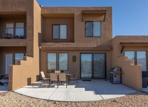 A modern two-story building with a patio area featuring outdoor seating and a barbecue grill. - Sunny Ledgeview Retreat (St. George)