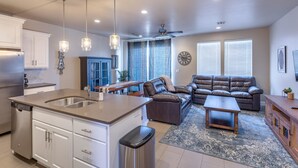 A modern kitchen with a central island, white cabinetry, stainless steel appliances, and pendant lighting. - Sunny Ledgeview Retreat (St. George)