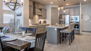 A modern kitchen with a central island, pendant lighting, and built-in appliances. - Fun At The Ledges (St. George)